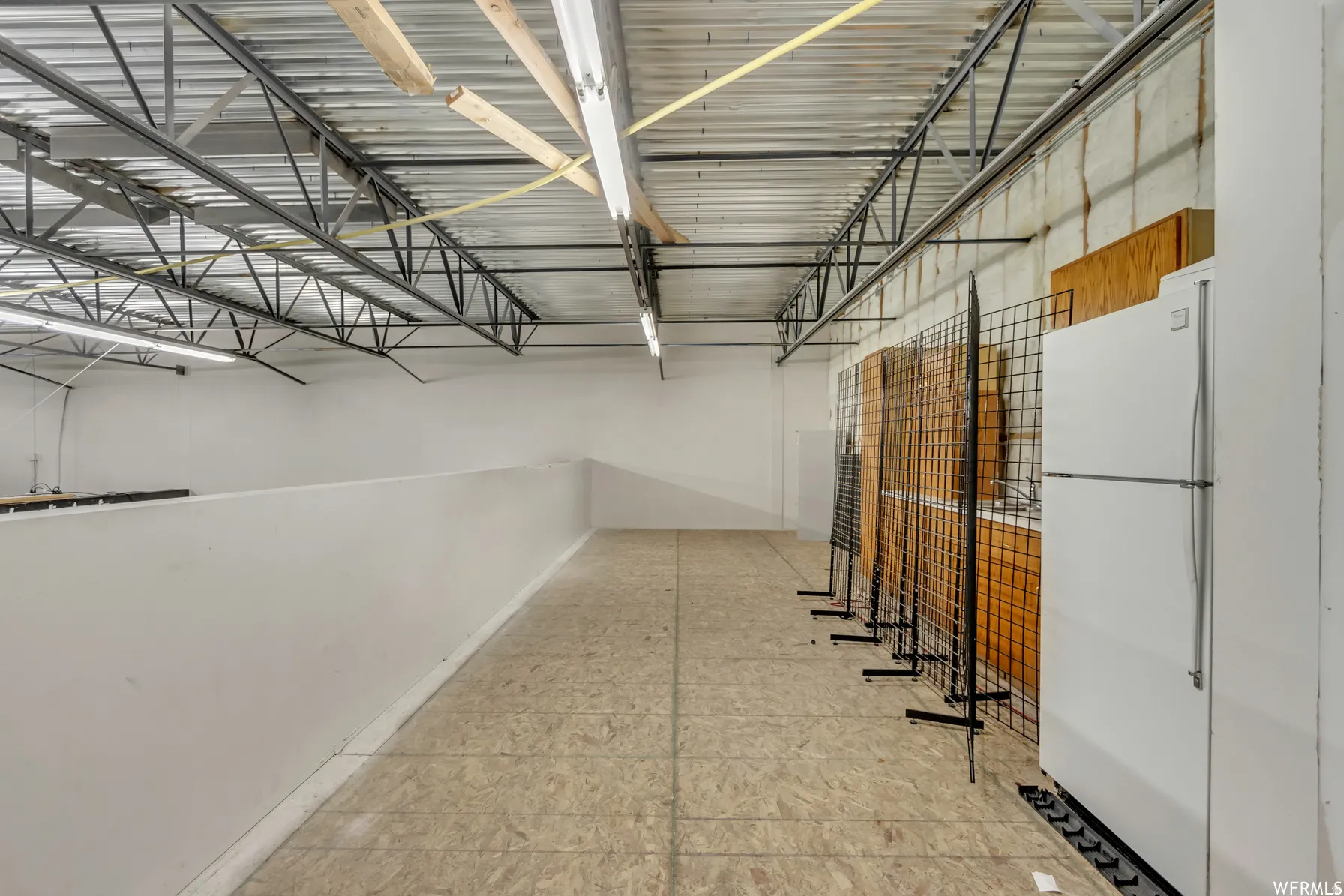 Upper level mezzanine featuring particle board flooring and white painted walls