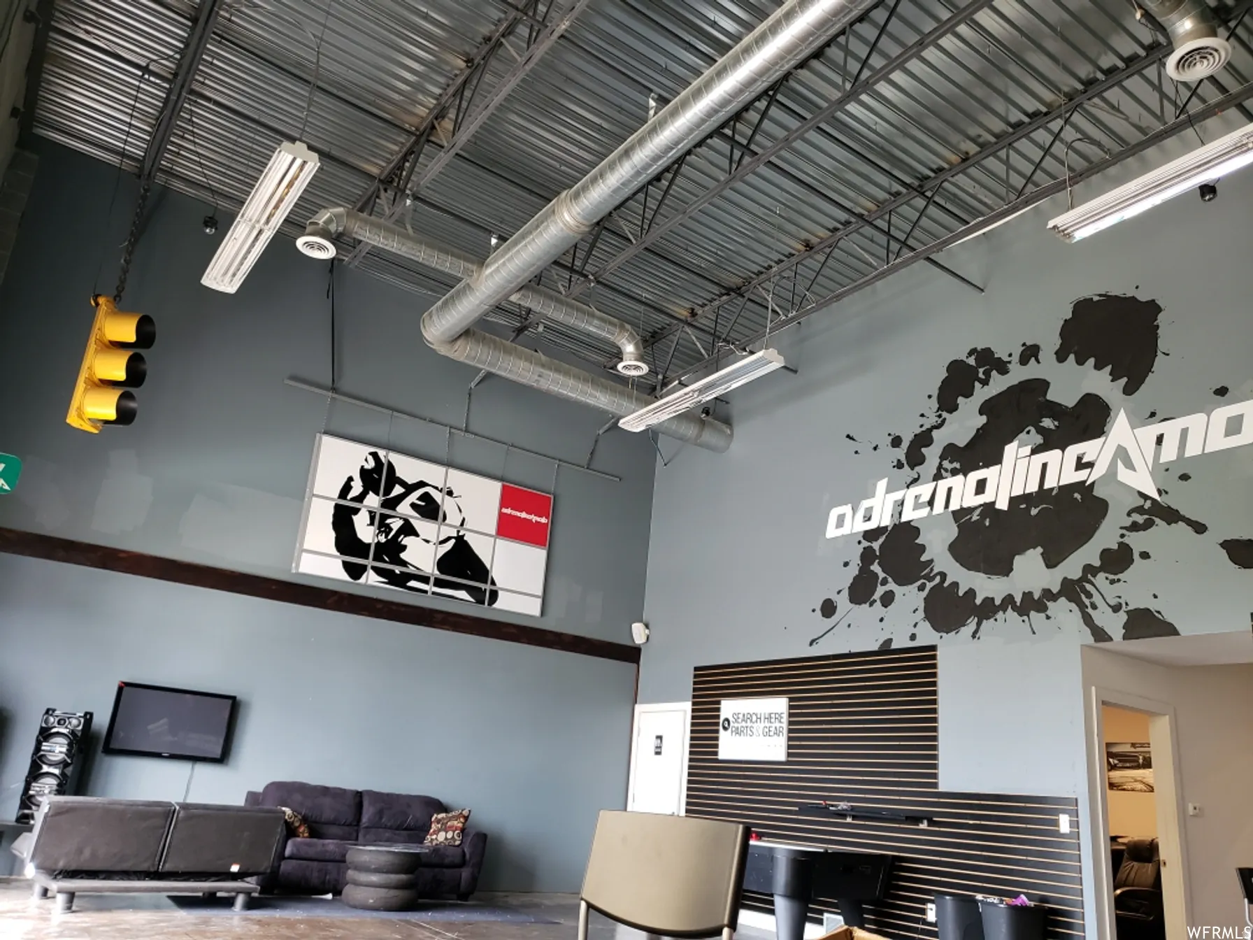 Exposed industrial ceiling featuring ductwork and fluorescent lighting