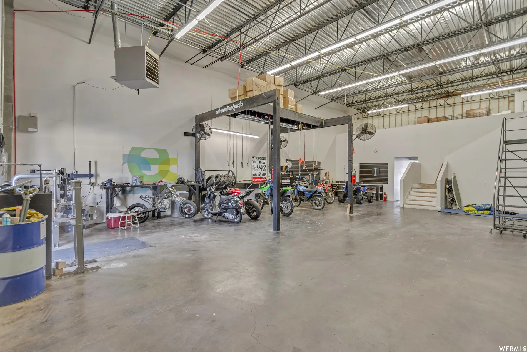 Spacious industrial interior featuring a concrete floor, exposed metal truss ceiling, and ample overhead lighting