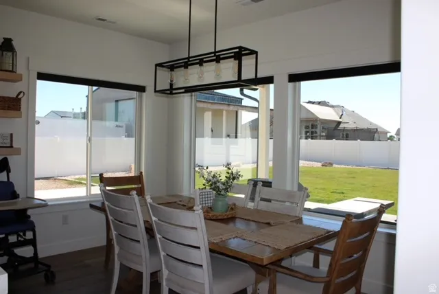 Dining area with wood-finish flooring and a contemporary linear chandelier