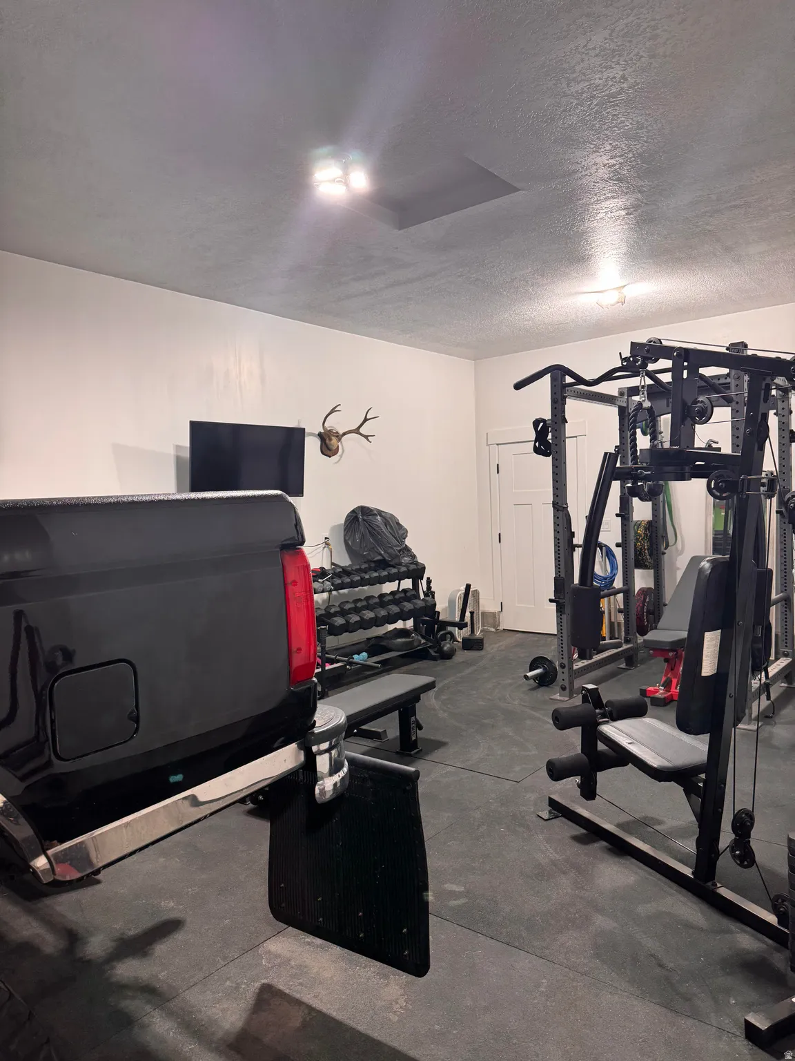 Spacious garage featuring durable rubber flooring, white painted walls, and overhead lighting
