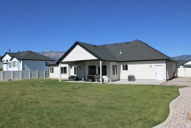 Spacious backyard featuring a large concrete patio, covered patio area, and a gravel border along the lawn