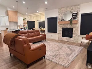 Spacious living area featuring light wood-finish flooring and a stone-clad fireplace with a natural wood mantel