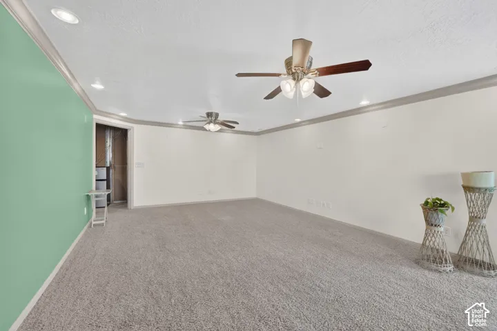 Spacious room featuring neutral carpeting, recessed lighting, crown molding, and multiple ceiling fans