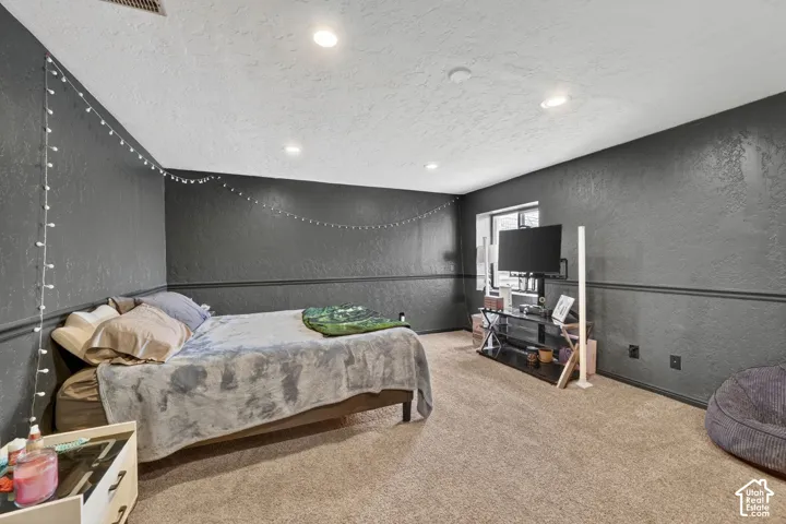 Carpeted room featuring textured dark gray walls with chair rail molding