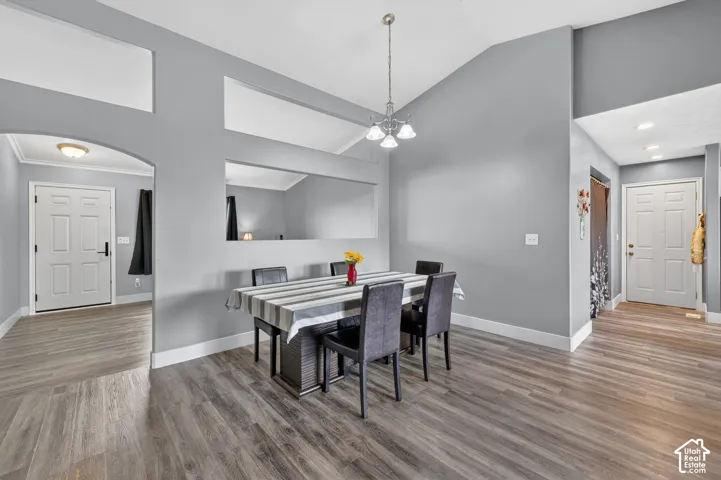 Vaulted ceilings with architectural wall cutouts enhance this dining area, featuring wood-finish flooring and a contemporary chandelier