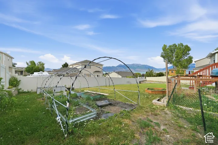Expansive backyard featuring a greenhouse frame, multiple raised garden beds, and a perimeter fence