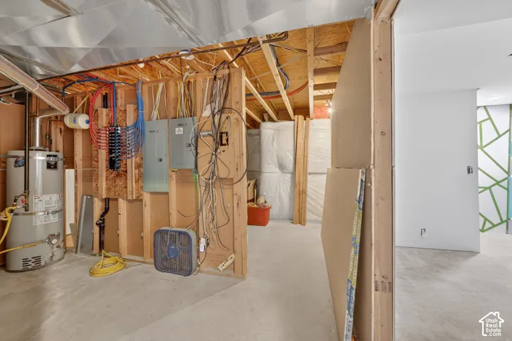 Unfinished basement area featuring exposed wood framing, concrete flooring, and a water heater
