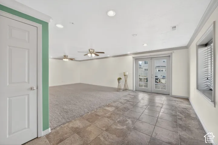Spacious room featuring a combination of tiled and carpeted flooring, French doors, recessed lighting, and multiple ceiling fans
