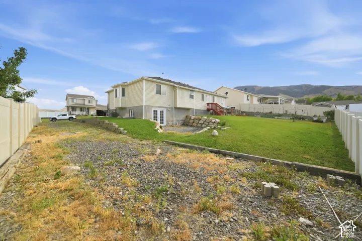 Expansive backyard area featuring a graded lawn, vinyl fencing, and a terraced landscape