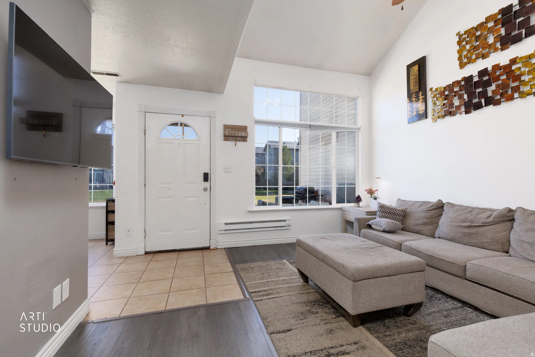Entryway featuring a white paneled door with an arched transom window, leading to a living area with vaulted ceilings