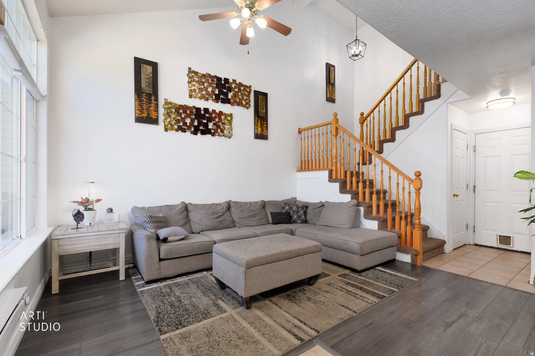 Living area featuring high vaulted ceilings, dark wood-finish flooring, a wood staircase with carpeted treads, and a multi-pane window