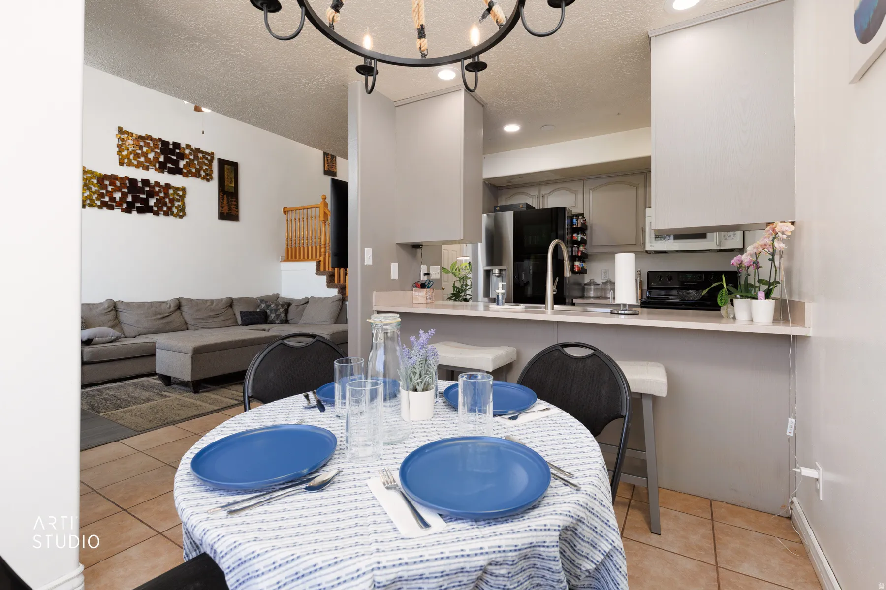 Open concept living space with tile flooring, a kitchen bar, light-toned cabinetry, and a full suite of kitchen appliances