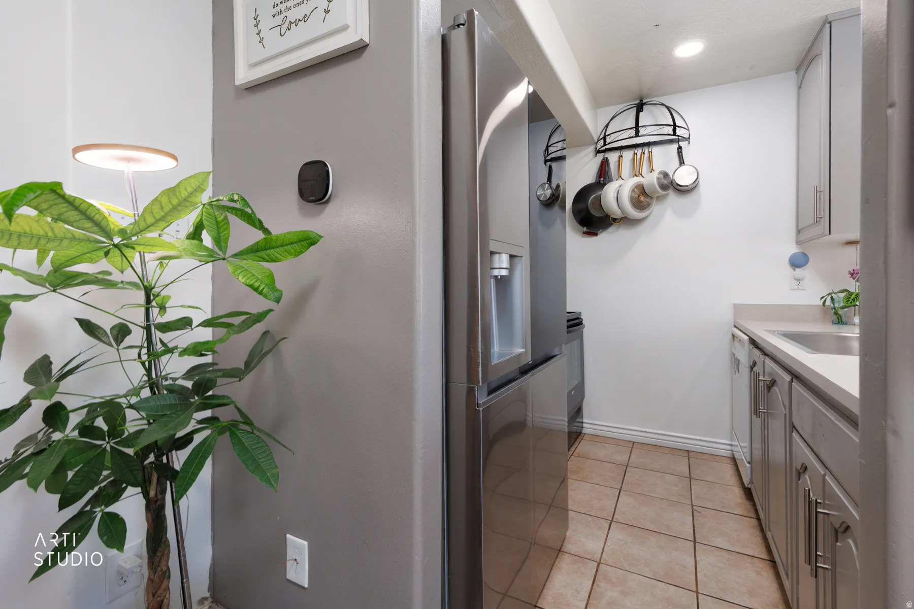 Kitchen area featuring stainless steel refrigerator, light-toned countertops, and light gray cabinetry with brushed nickel hardware