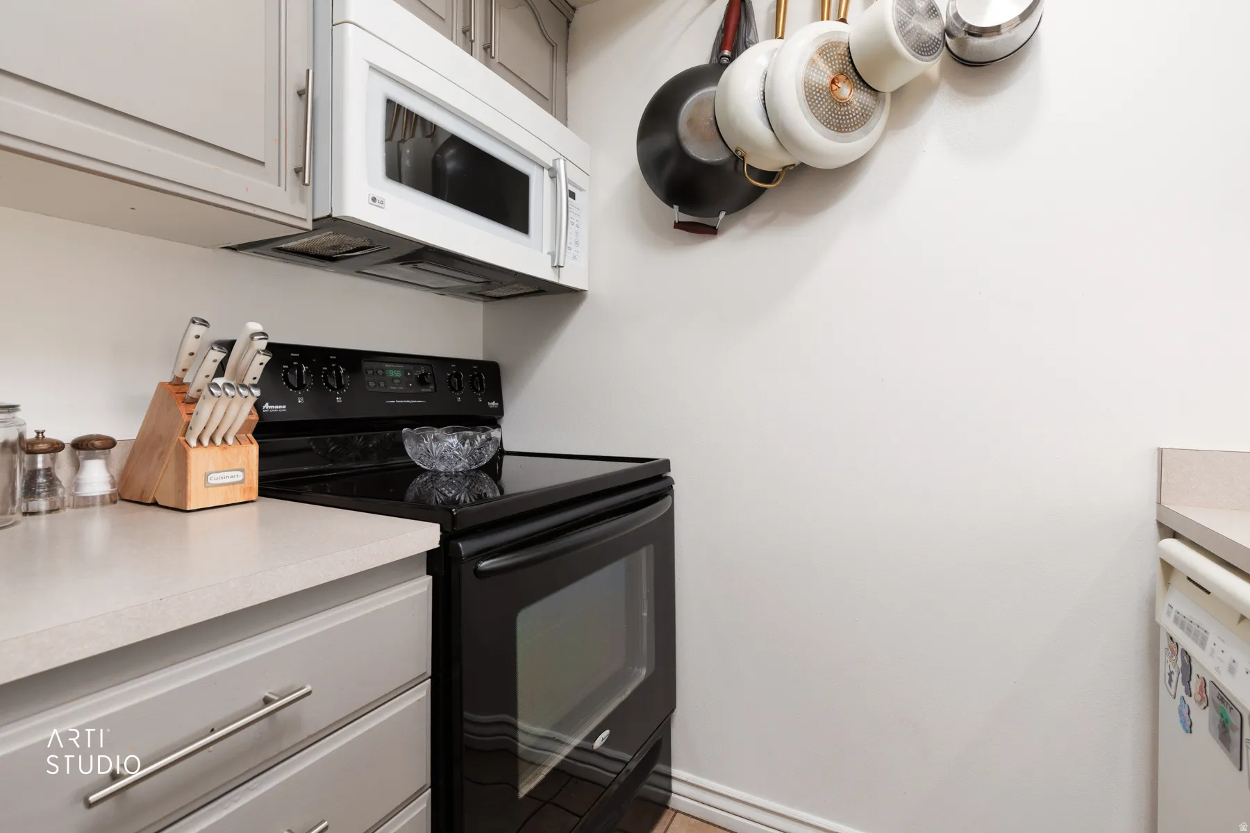 Kitchen featuring a black electric range, white over-the-range microwave, light gray cabinetry, and light-toned countertops