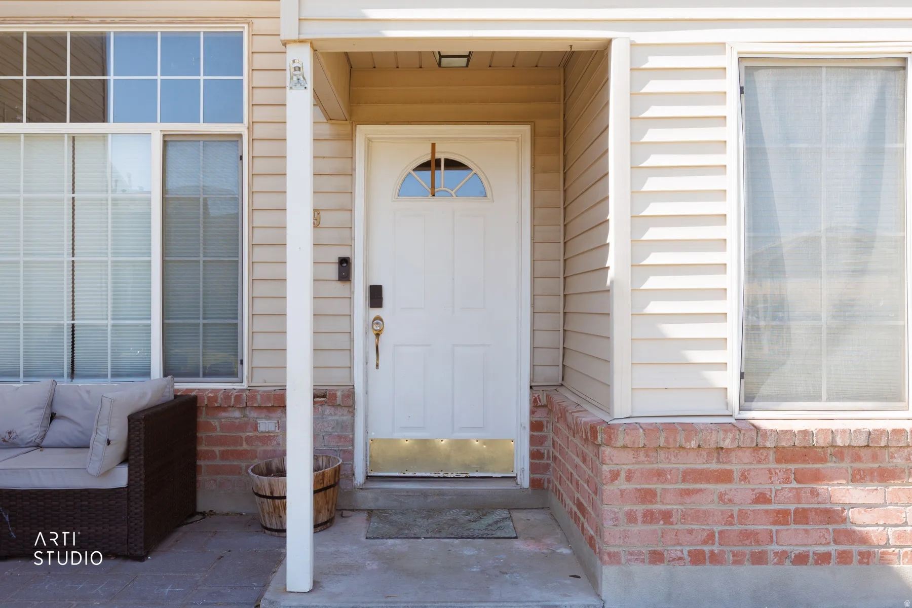 Inviting entryway featuring a white paneled door with an arched window, complemented by brick detailing and horizontal siding