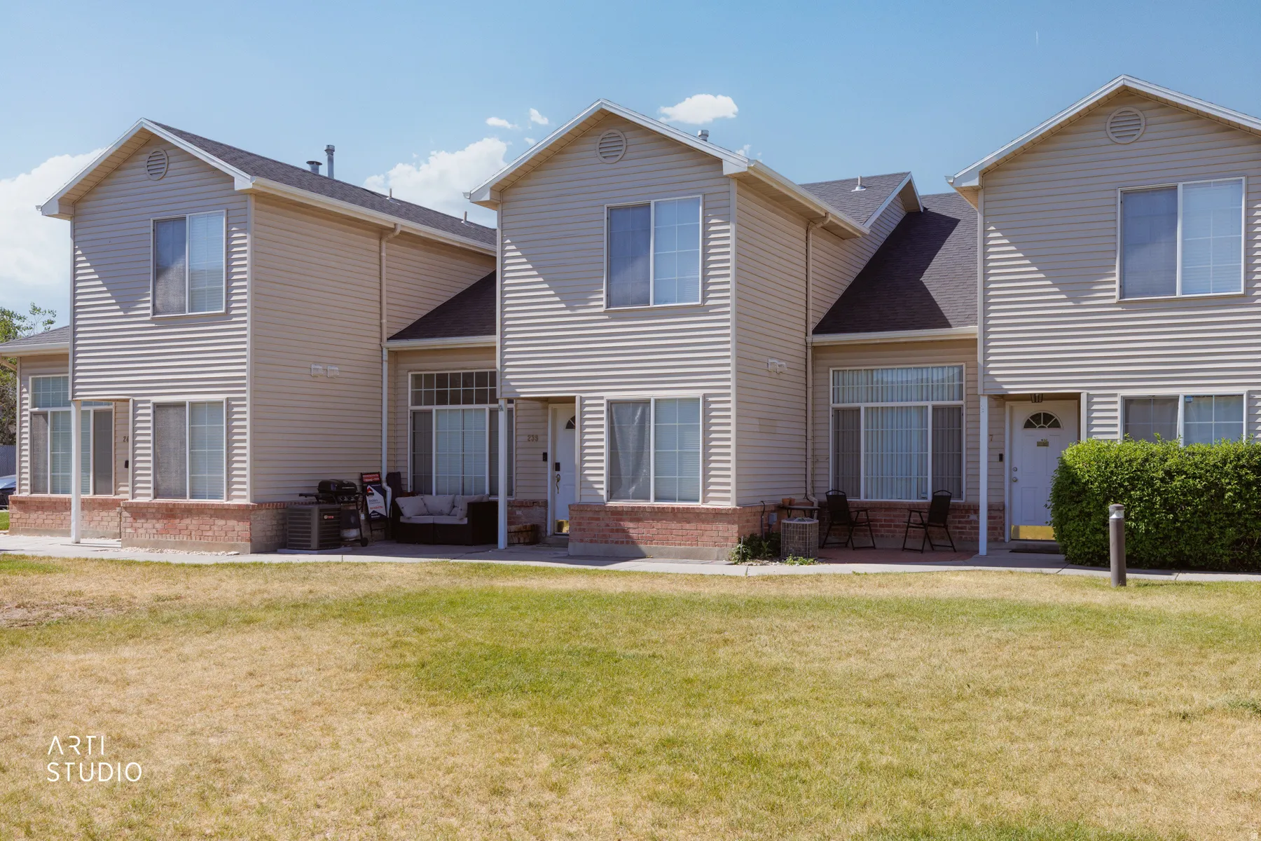 Multi-level residential building featuring light-colored siding and dark shingle roofing