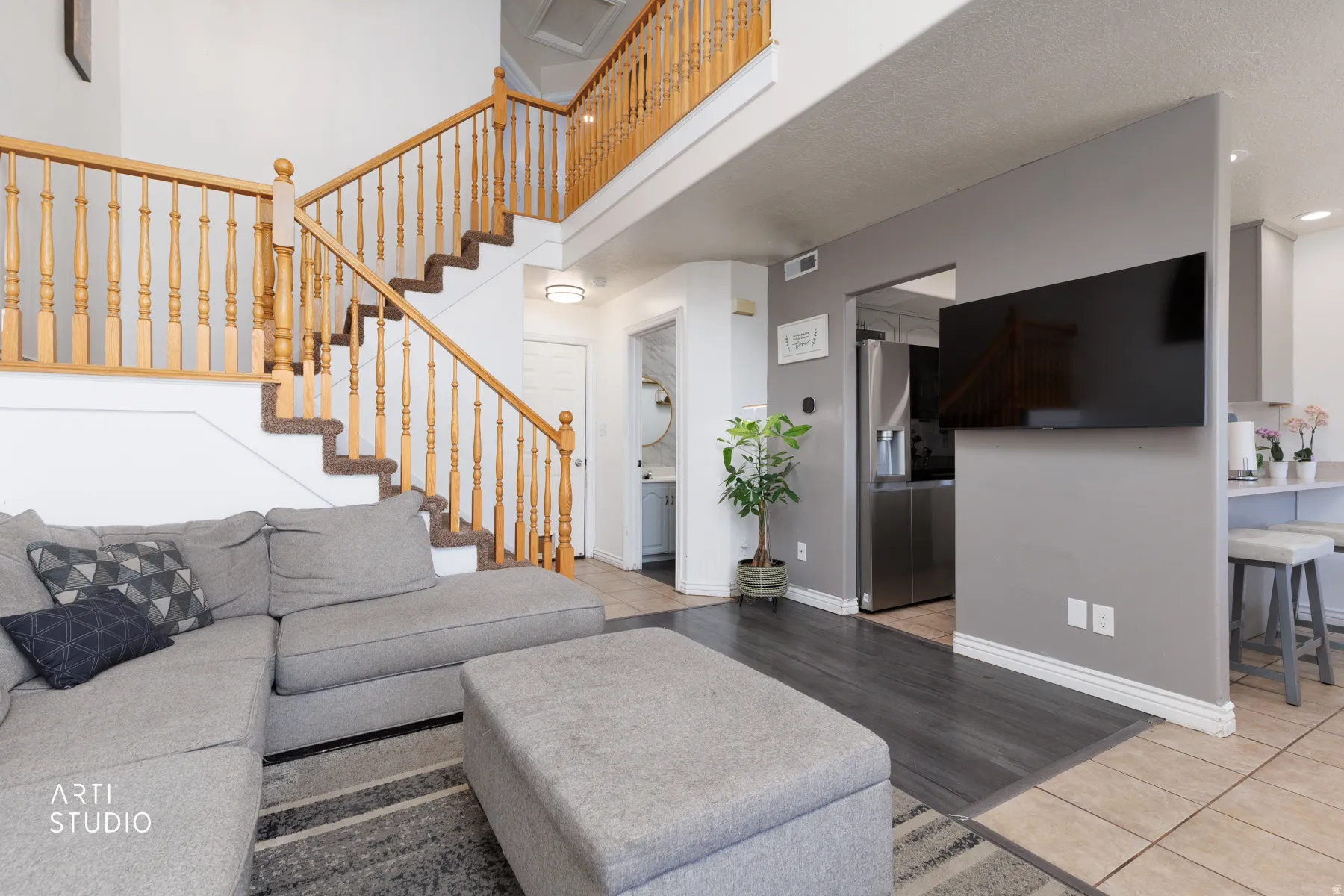 Two-story interior featuring a staircase with wood banisters and carpeted treads, wood-finish flooring, and a partial wall separating living spaces