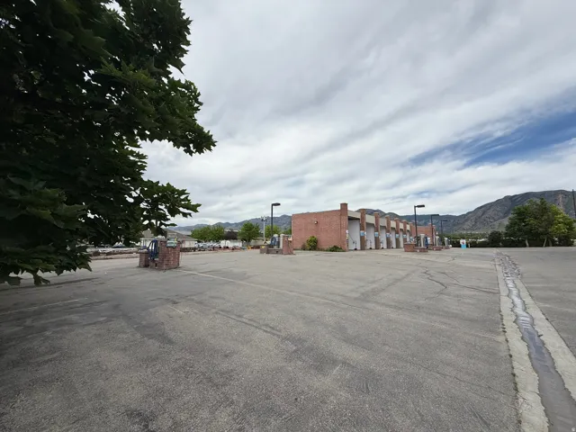 Paved parking area with brick pillar accents and commercial building with multiple bays