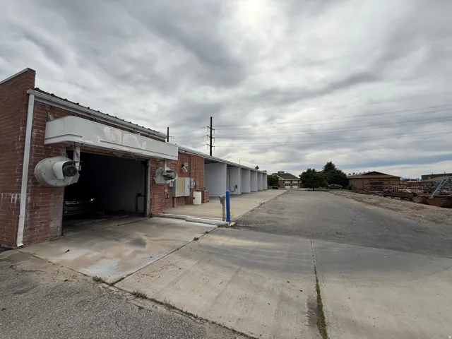 Brick facade structure with a drive-through bay, multiple additional bays, and an expansive paved lot