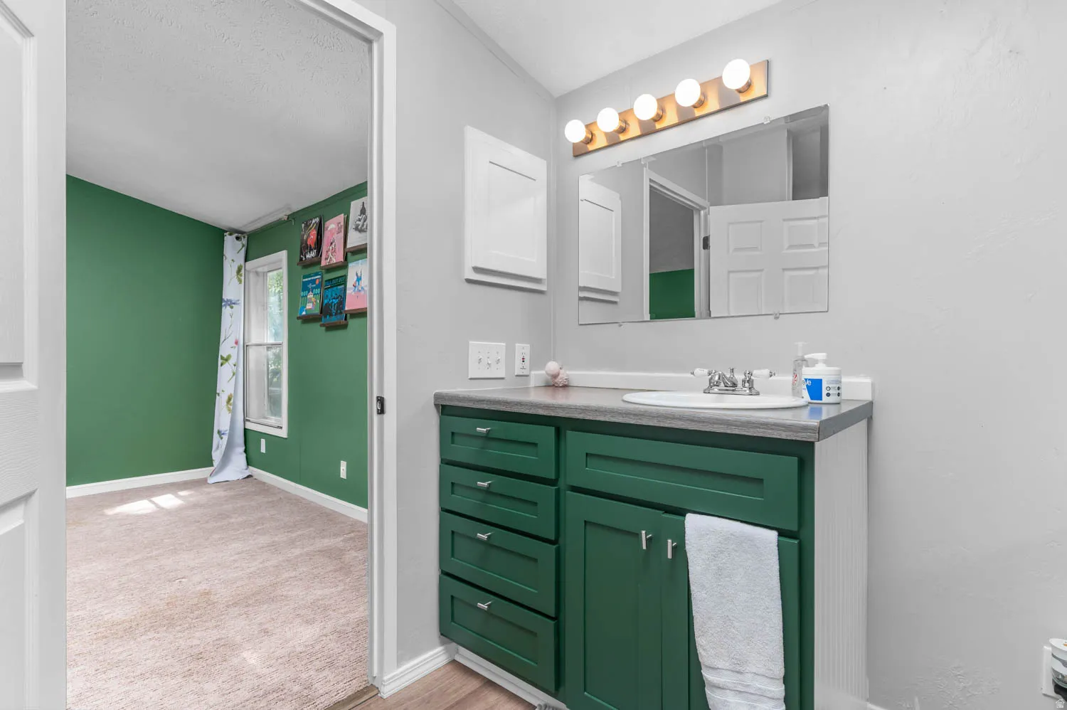 Bathroom vanity with a green base cabinet, a white sink, and a countertop