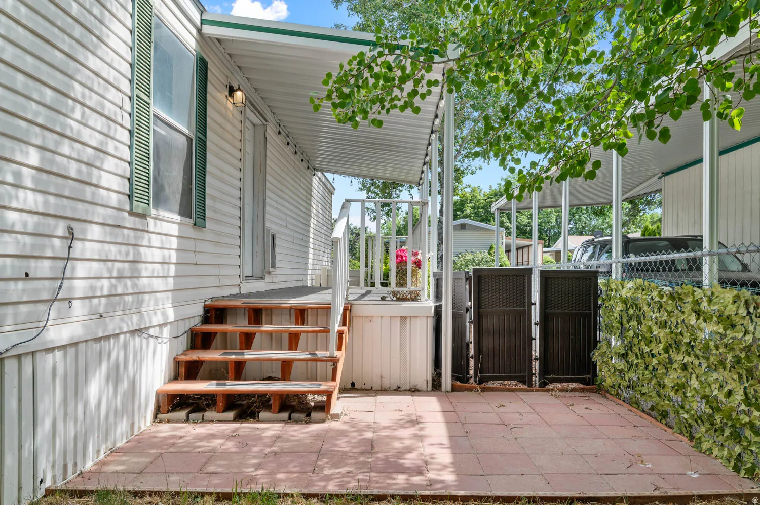 Covered porch with wooden stairs and a patio featuring red pavers