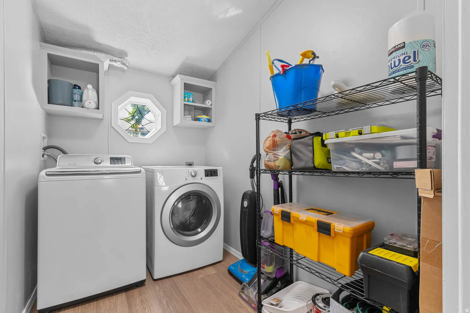 Dedicated utility space featuring wood-finish flooring and light gray wall paneling