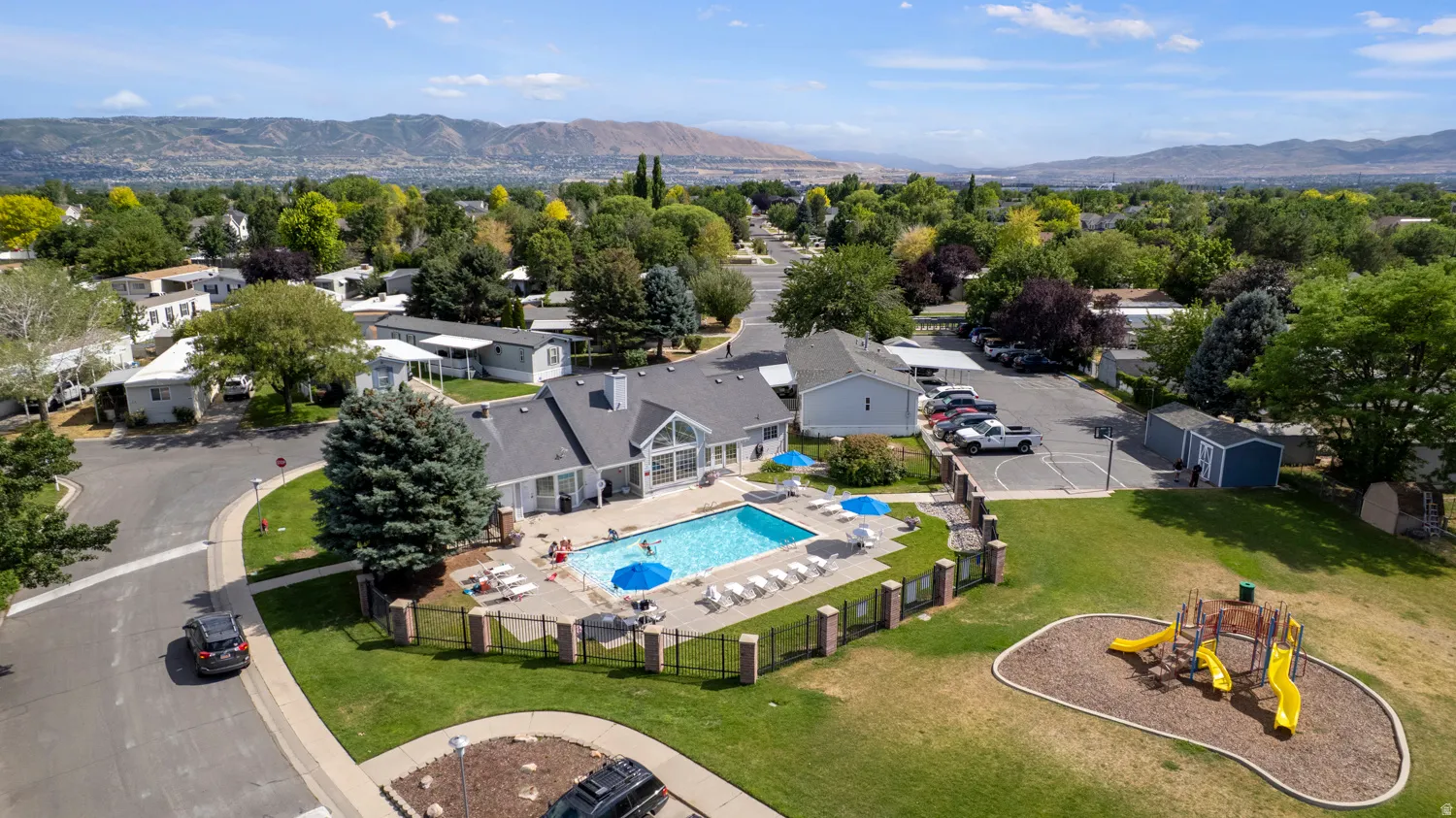 Recreational hub featuring a large swimming pool, surrounding patio, and a separate fenced playground area with multiple slides