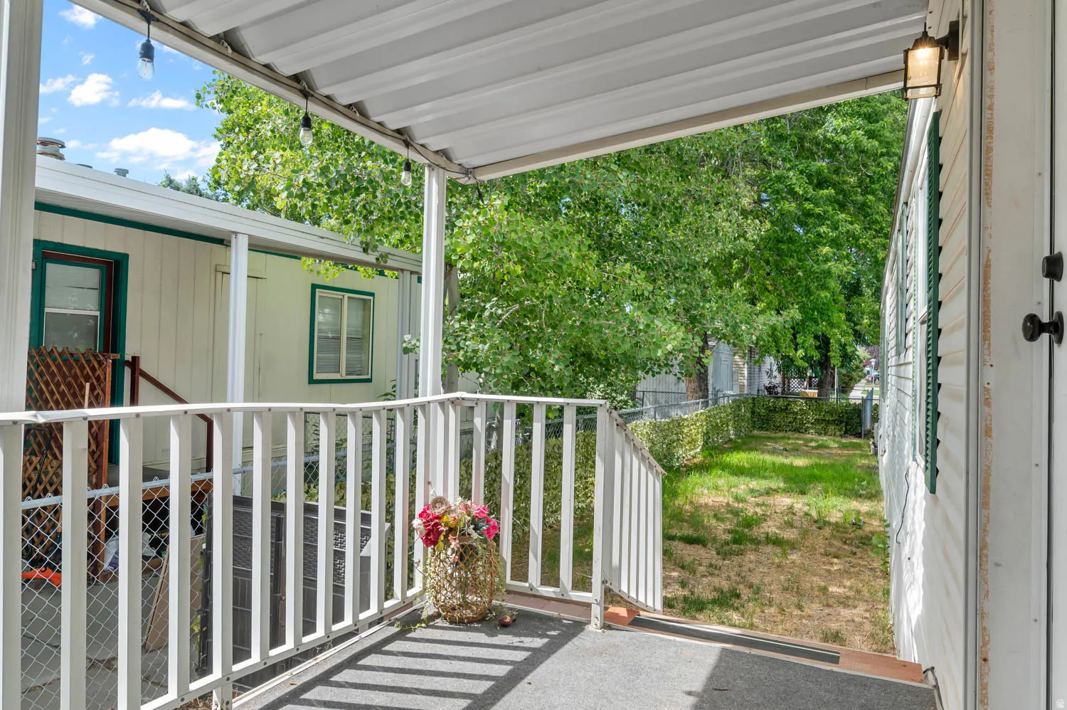 Covered porch entry featuring a white metal railing and outdoor lighting