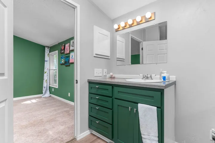 Bathroom vanity with a green base cabinet, a white sink, and a countertop