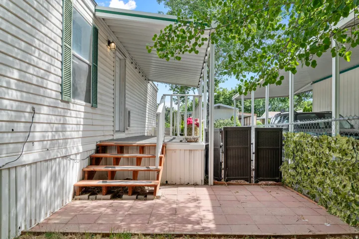 Covered porch with wooden stairs and a patio featuring red pavers