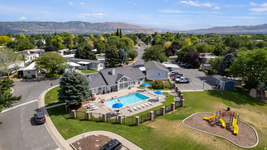 Recreational hub featuring a large swimming pool, surrounding patio, and a separate fenced playground area with multiple slides