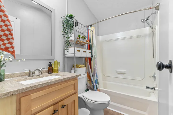 Bathroom featuring a light wood-finish vanity with a speckled countertop, a white rectangular sink, and a framed mirror