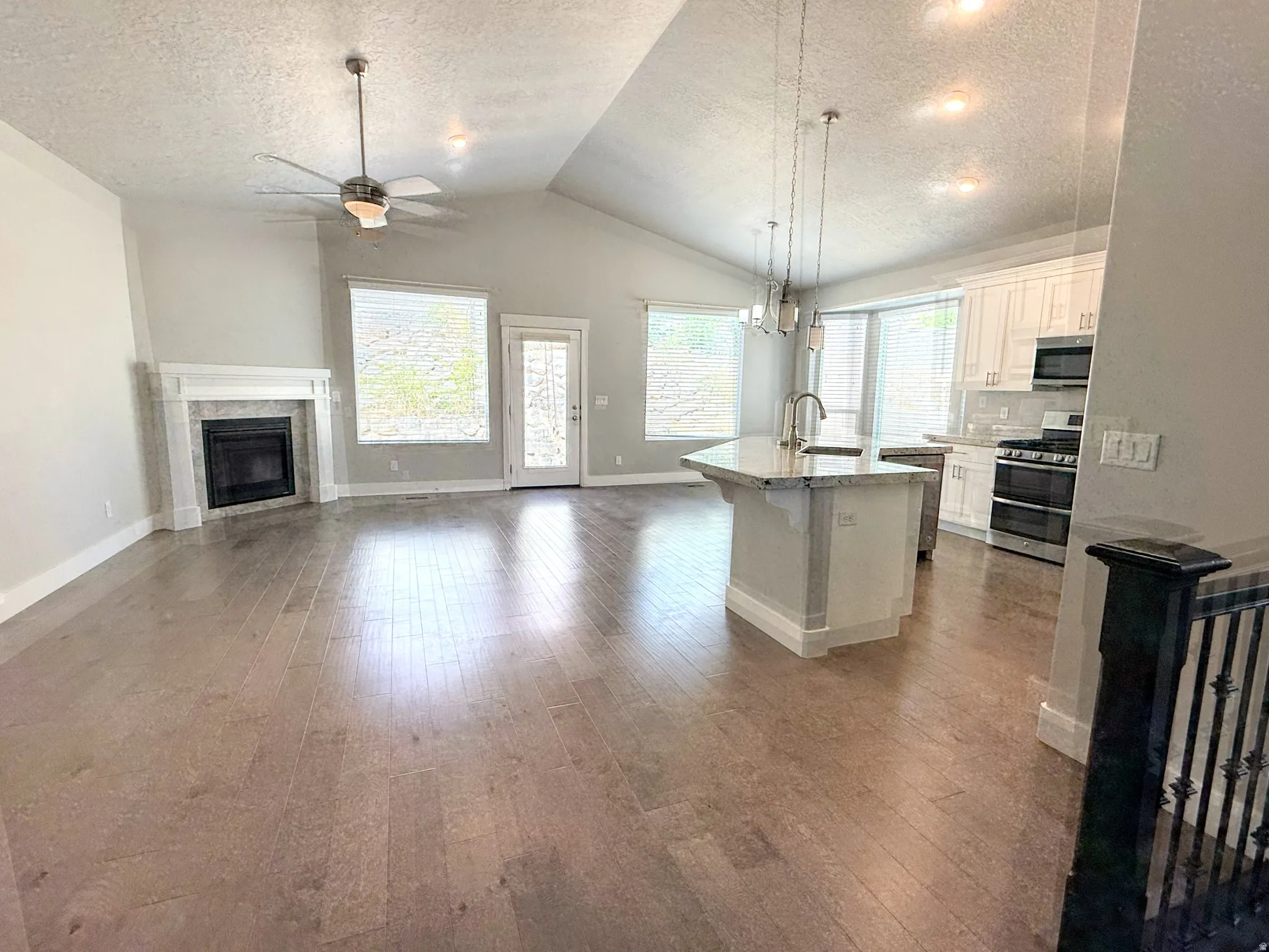 Open-concept living space featuring wood-finish flooring, a vaulted ceiling, and recessed lighting