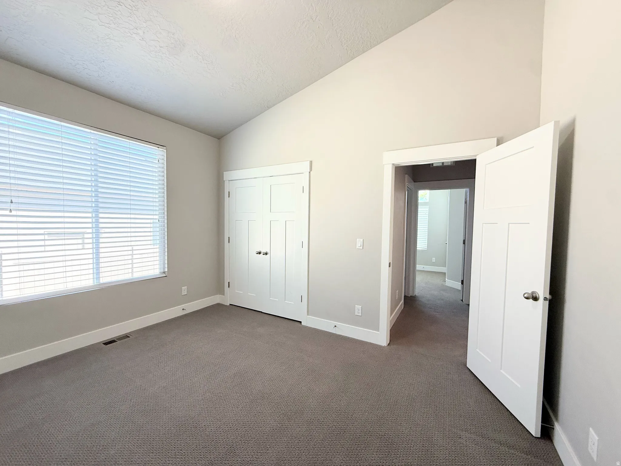 Bedroom #3 Carpeted interior space featuring a vaulted ceiling and a large window with blinds