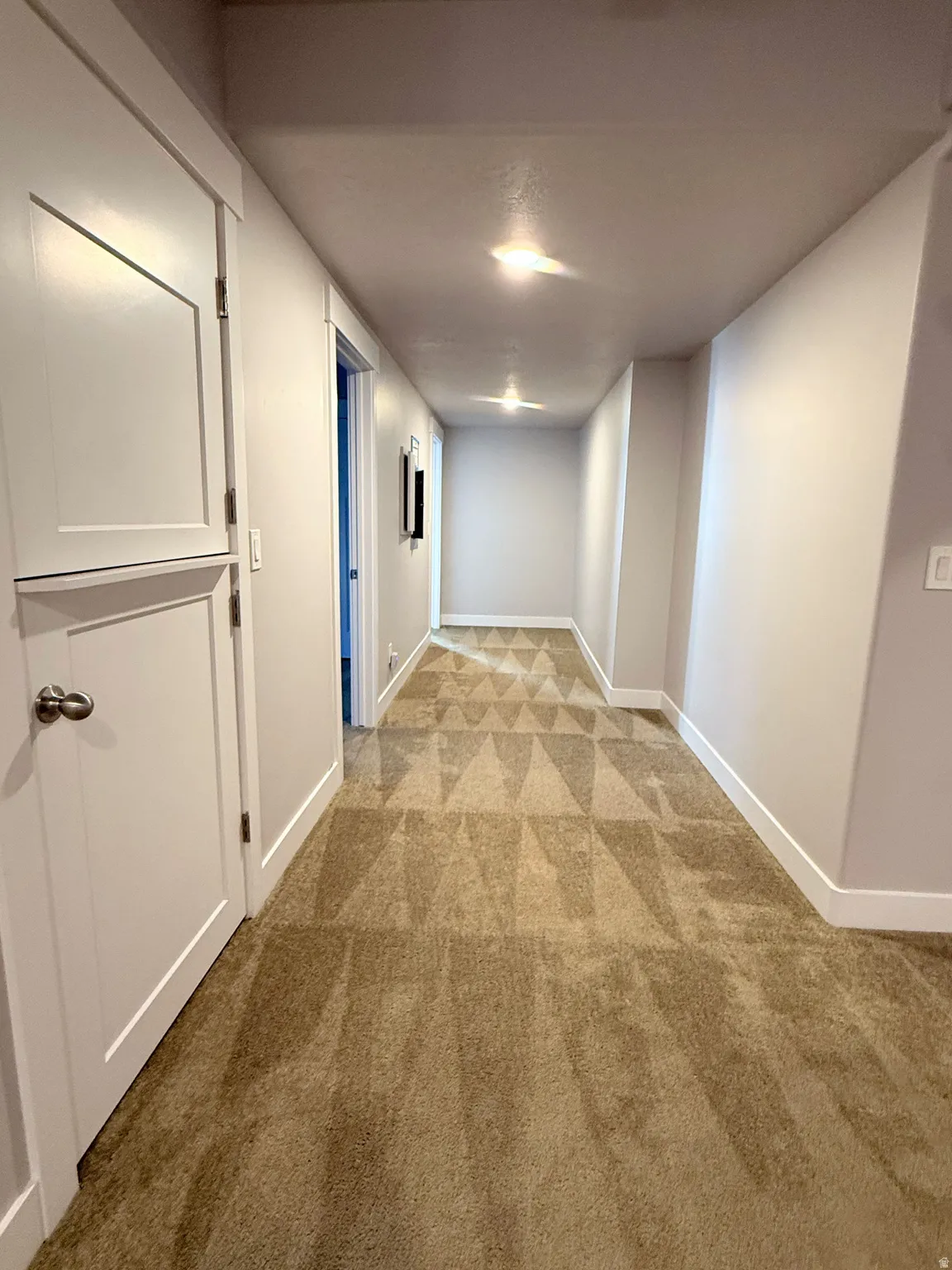 Long hallway with carpet flooring, recessed lighting, and white baseboards