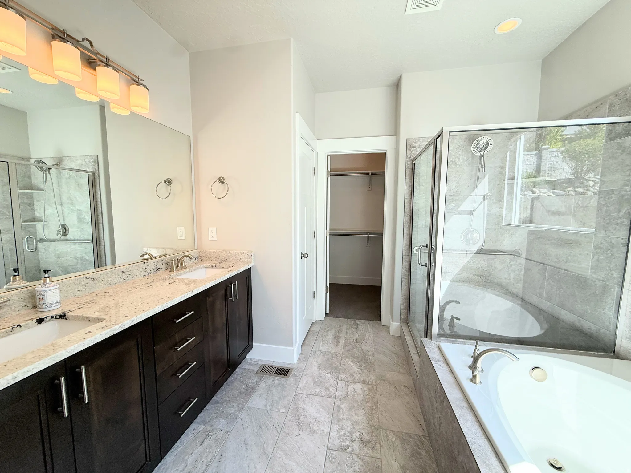 Primary Bathroom Suite featuring a dual vanity with granite countertop, dark wood cabinetry, and brushed nickel hardware