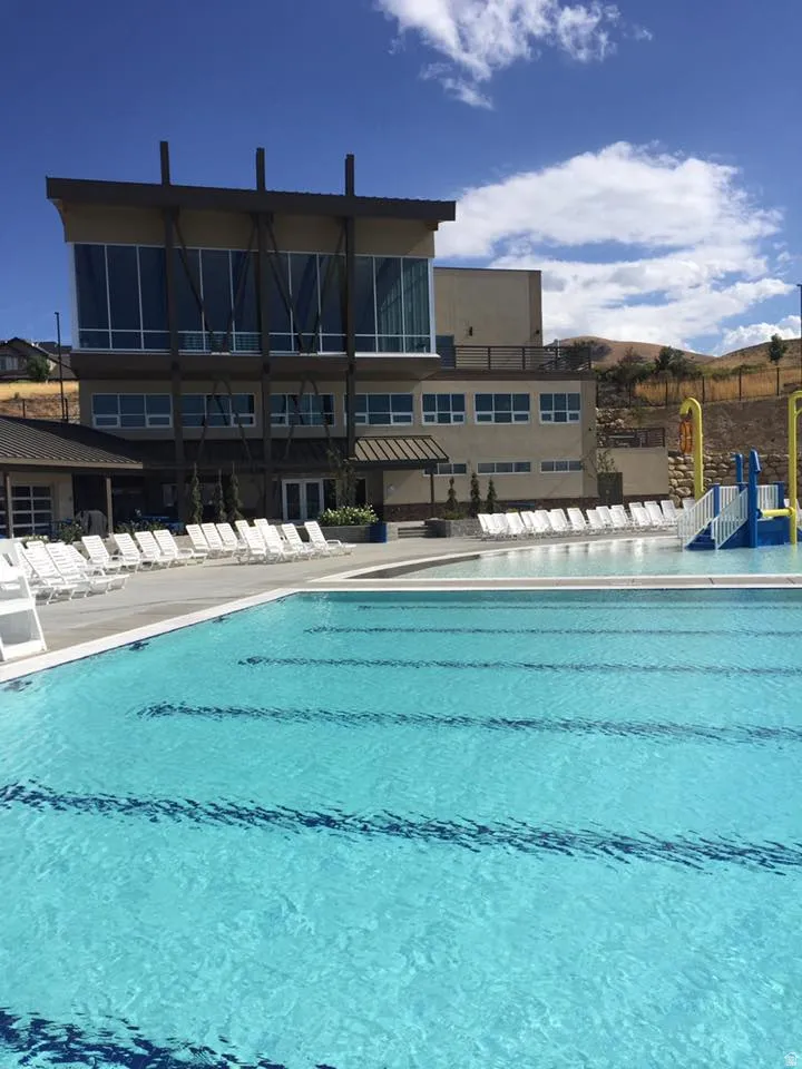 Community outdoor swimming pool featuring lane lines and a surrounding deck with lounge chairs and kid pool area