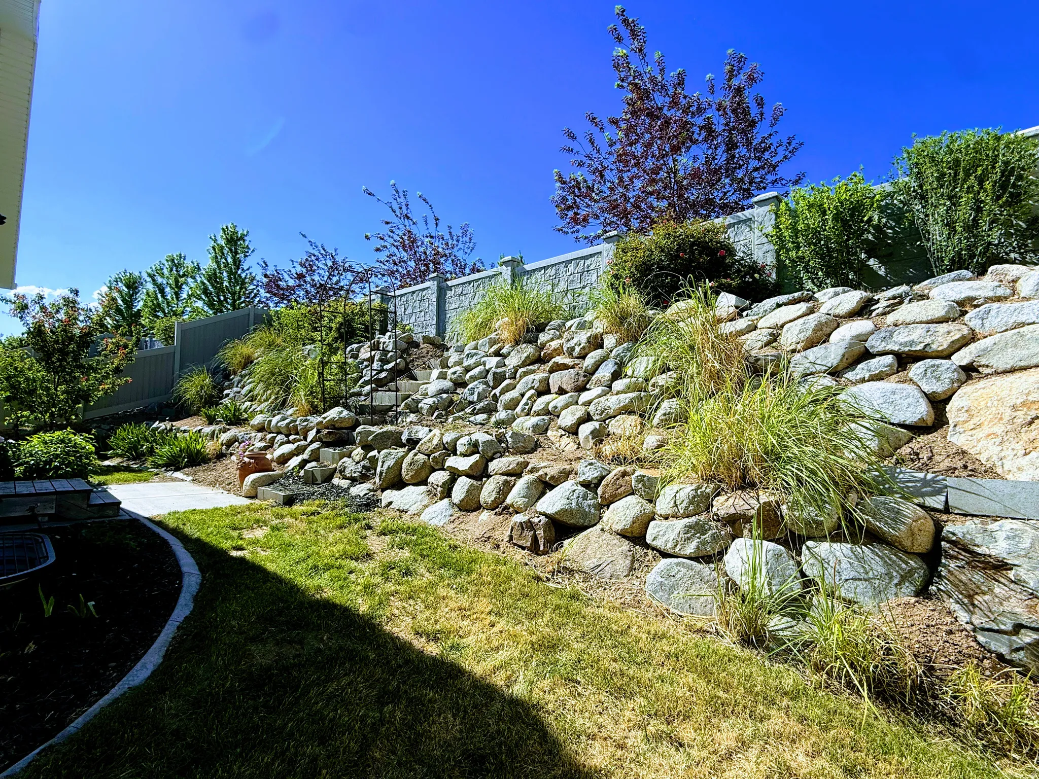 Terraced rock landscaping featuring a stone retaining wall and integrated plantings