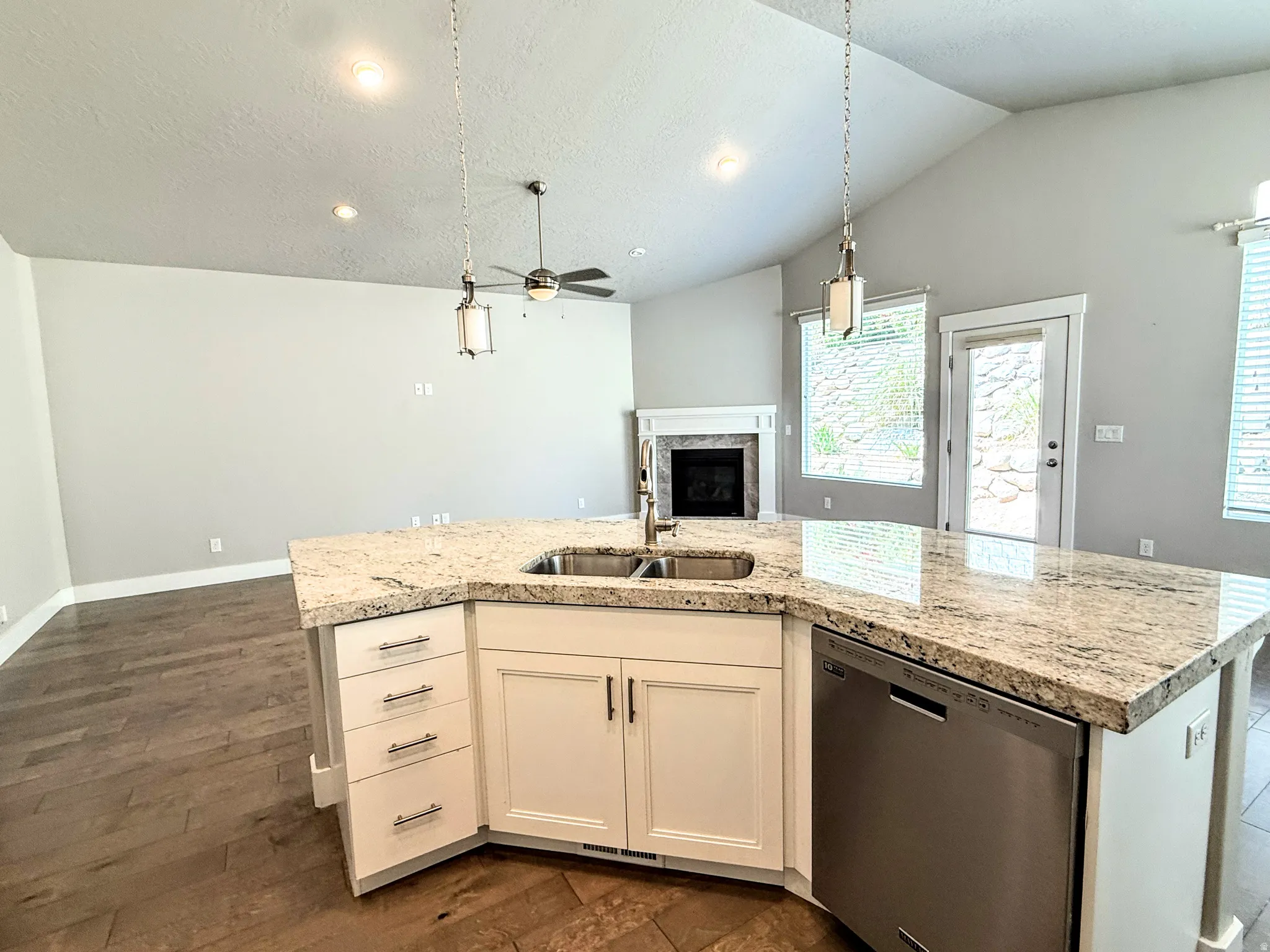 Kitchen island featuring a double-basin sink, stainless steel dishwasher, and stone-finish countertop