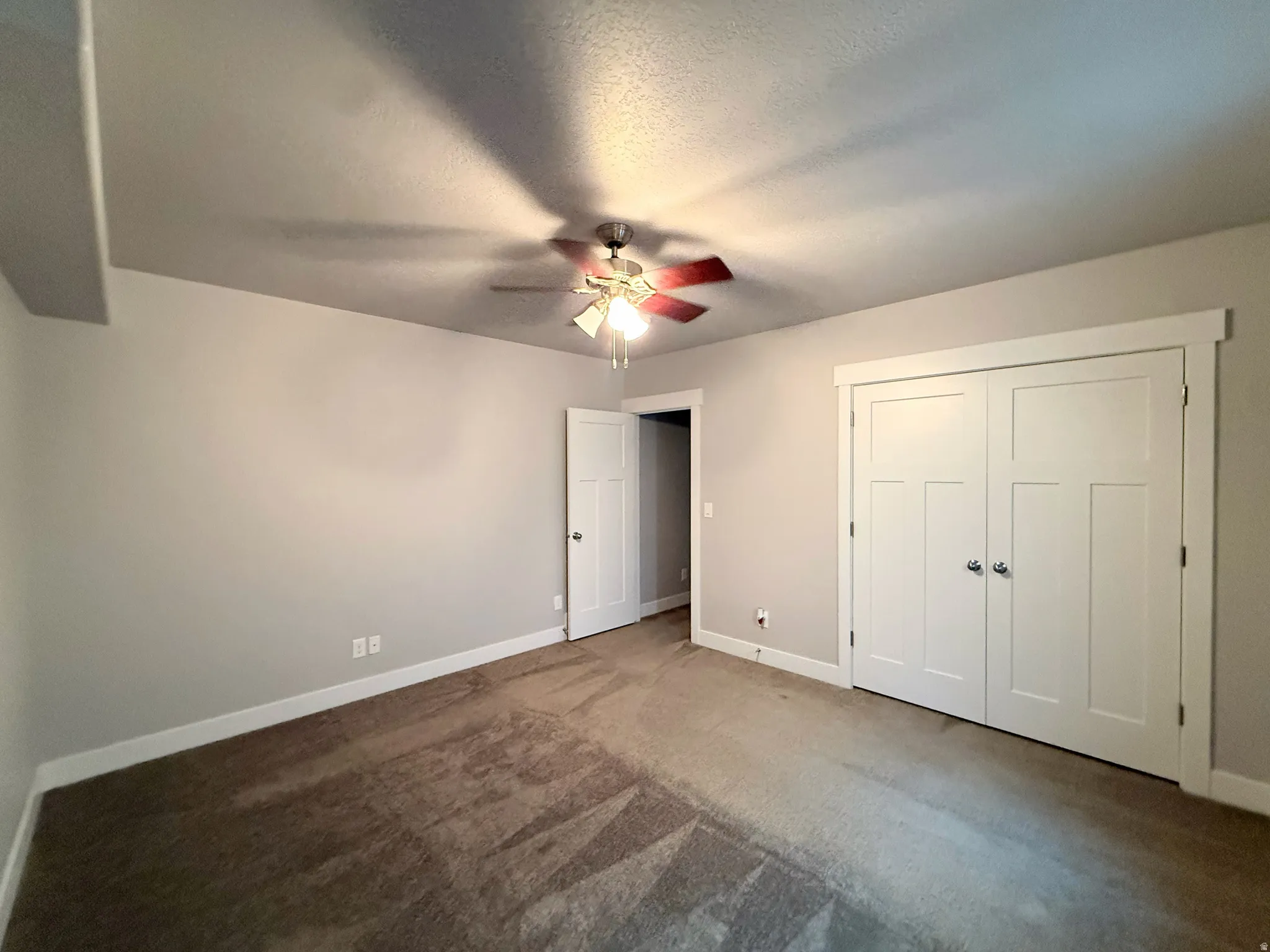 Bedroom #4 featuring light gray walls, a ceiling fan with integrated lighting, a white paneled door, and a white bi-fold closet with decorative trim