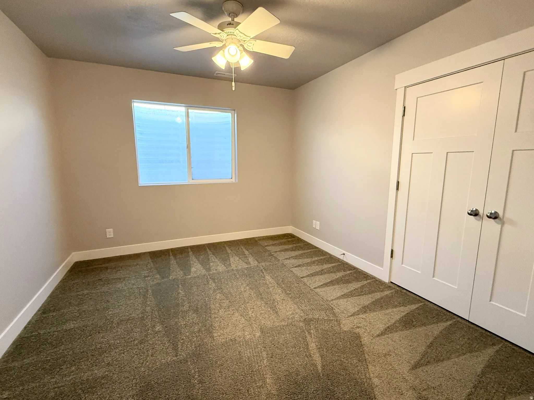 Bedroom #5 Carpeted interior room featuring a ceiling fan with integrated lighting, a window with horizontal blinds, and a double-door closet with chrome hardware