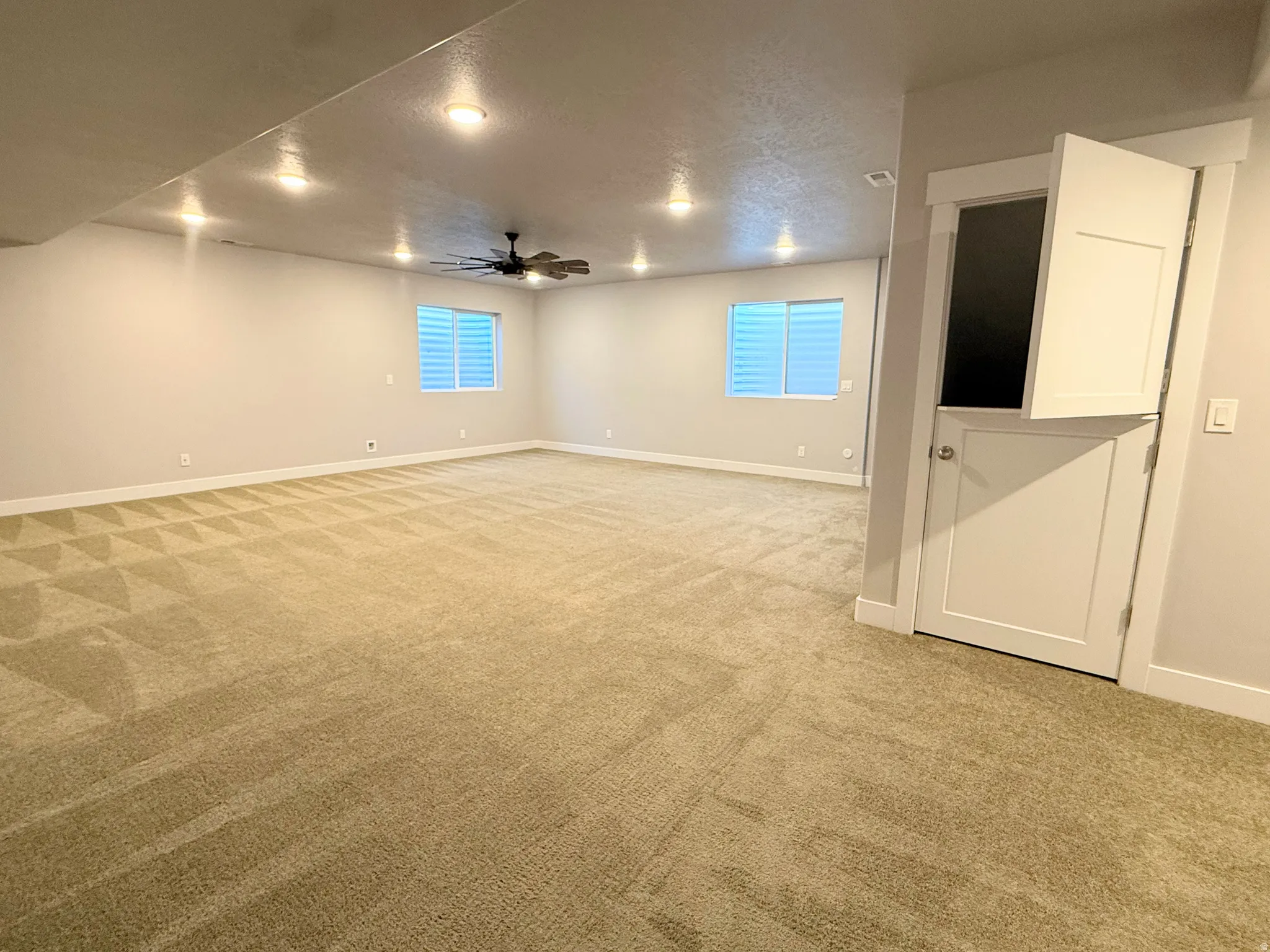 Spacious room featuring neutral carpeting, recessed lighting, and a ceiling fan