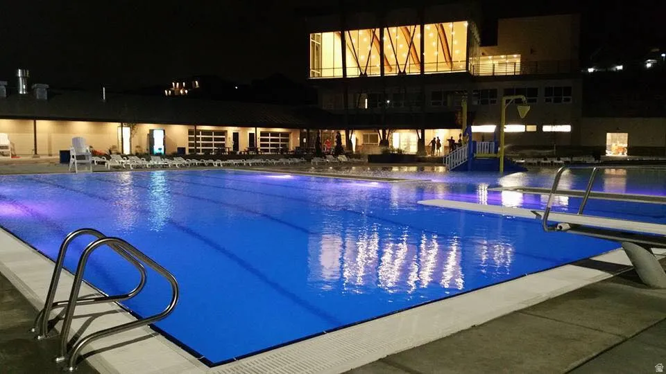 Community swimming pool featuring lane lines, stainless steel ladder, and diving board