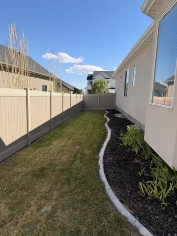 Private backyard with a manicured lawn, established landscaping, and durable fencing