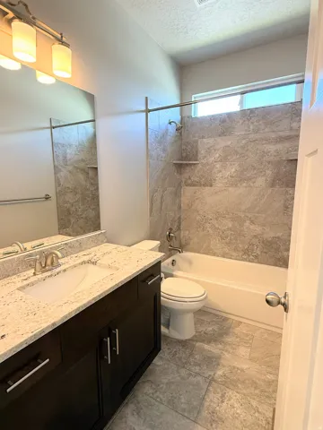 Bathroom #2 featuring a dark wood-finish vanity with a light-toned countertop, an undermount sink, and a large wall mirror