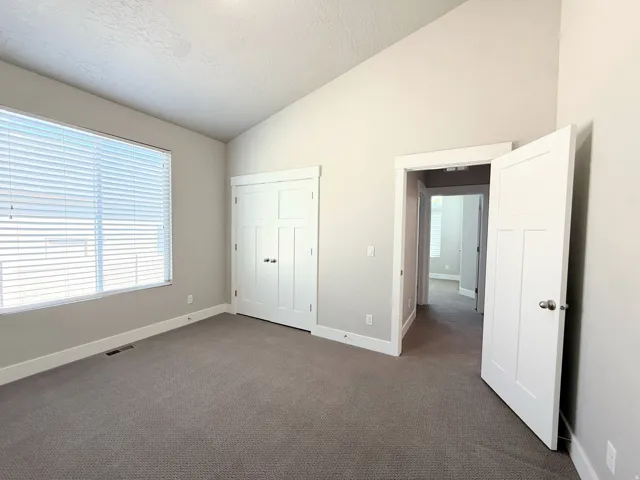 Bedroom #3 Carpeted interior space featuring a vaulted ceiling and a large window with blinds