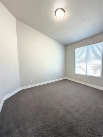 Bedroom #3 featuring neutral wall paint, dark carpet flooring, and a single window with horizontal blinds