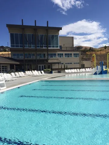 Community outdoor swimming pool featuring lane lines and a surrounding deck with lounge chairs and kid pool area
