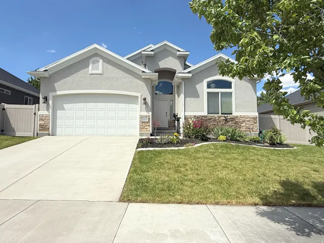 Contemporary stucco exterior featuring a stone accent foundation, arched entry, and a two-car garage